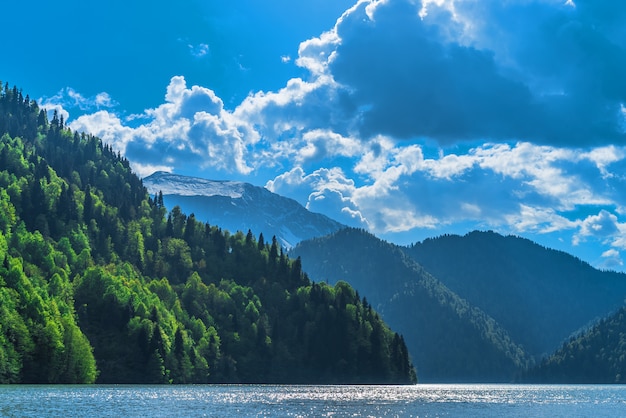 Schöner See Ritsa im Kaukasus. Grüne Berghügel, blauer Himmel mit Wolken. Frühlingslandschaft.