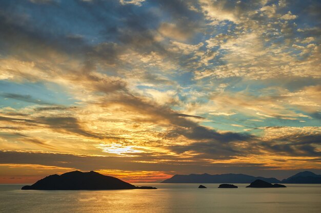 Schöner Sonnenuntergang Himmel mit Wolken über dem Meer Sonnenlicht Blendung auf dem Wasser Silhouetten einer Reihe von Inseln am Horizont Idee für Hintergrund oder Tapete Atemberaubende dramatische Sonnenuntergang Urlaubszeit