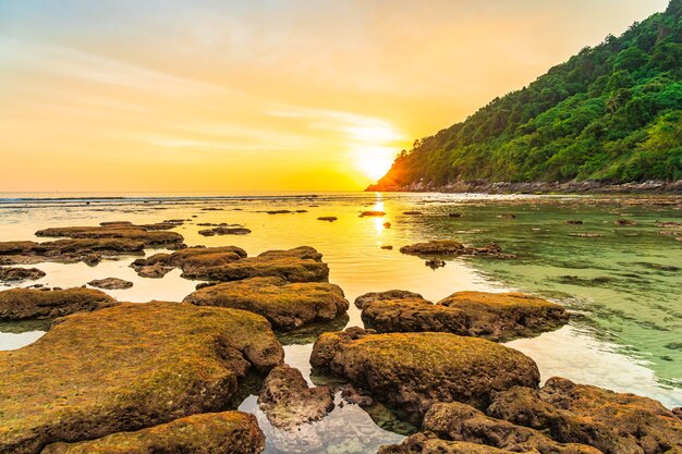 Schöner Sonnenuntergang über Berg um Strandmeerozean und Felsen