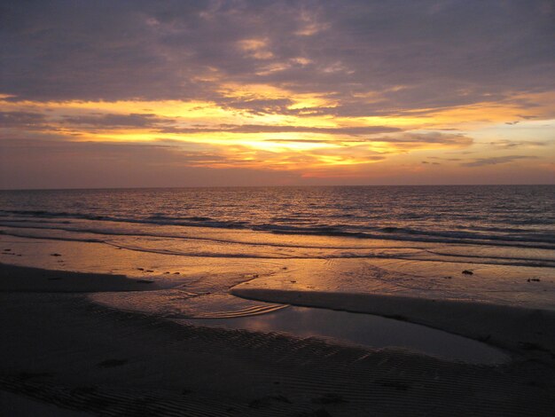 Schöner Strand und das Meer unter dem bunten Himmel bei Sonnenuntergang