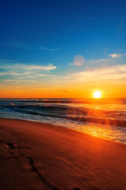 Schöner Strandsonnenaufgang unter einem blauen Himmel