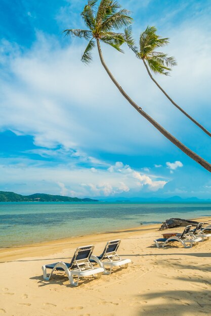 Schöner tropischer Strand und Meer mit KokosnussPalme und Stuhl in der Paradiesinsel