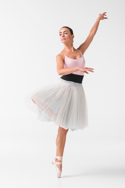 Schöner weiblicher Tänzer im eleganten weißen Ballettröckchen gegen weißen Hintergrund