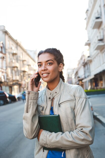 Schönes afrikanisches Mädchen, das auf dem Handy spricht