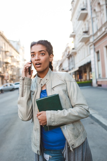 Schönes afrikanisches Mädchen, das auf dem Handy spricht