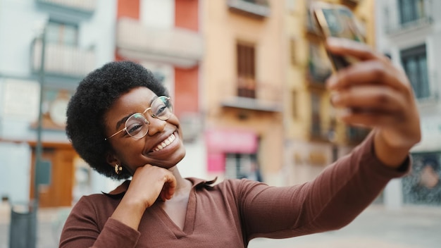 Schönes afroamerikanisches Mädchen lächelt und macht Selfie auf der Straße