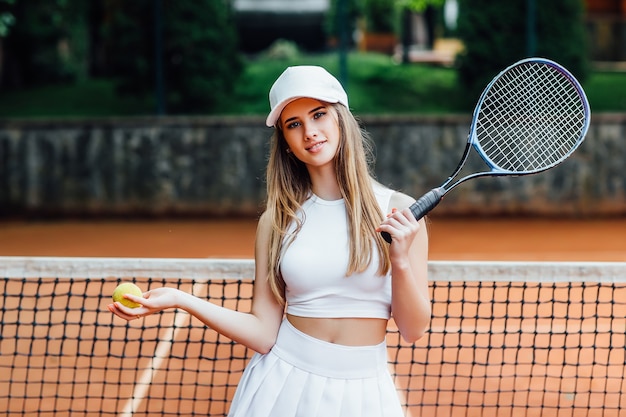 Schönes Bild einer jungen glücklichen Frau in Sportkleidung, Tennis spielend, auf den Aufschlag wartend.