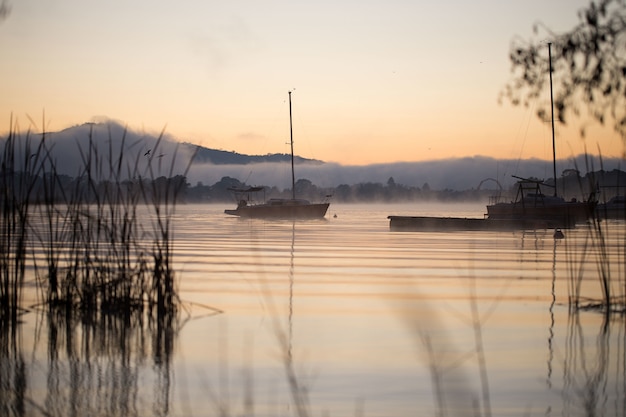 Kostenloses Foto schönes bild eines hypnotisierenden sonnenuntergangs, der auf dem wasser gegen die berge reflektiert