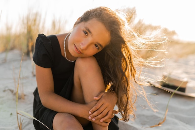 Schönes brunettekindmädchen, das om den strand aufwirft warme farben des sonnenuntergangs