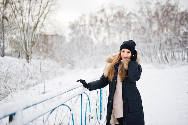 Schönes Brunettemädchen in der warmen Winterkleidung Modell auf Winterjacke und schwarzem Hut