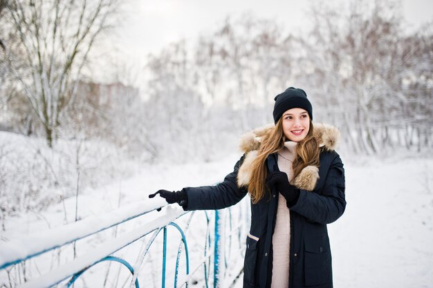 Schönes Brunettemädchen in der warmen Winterkleidung Modell auf Winterjacke und schwarzem Hut