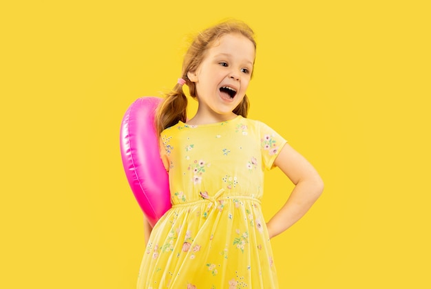 Schönes emotionales kleines Mädchen lokalisiert auf Gelb