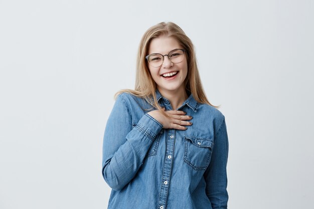 Schönes europäisches Mädchen sieht mit Freude aus, zeigt weiße perfekte Zähne, drückt Positivität aus, froh, Erfolg mit nahen Leuten zu teilen, isoliert. Glückskonzept