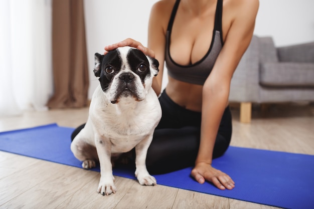 Schönes Fitnessmädchen, das auf Boden mit Hund sitzt