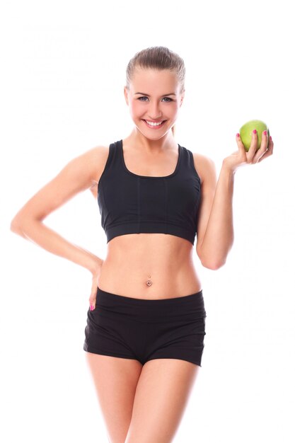 Schönes Fitnessmädchen mit grünem Apfel in der Hand