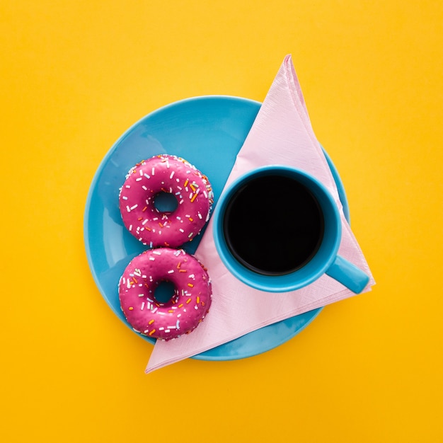 Schönes Frühstück mit Donut und Tasse Kaffee auf Gelb