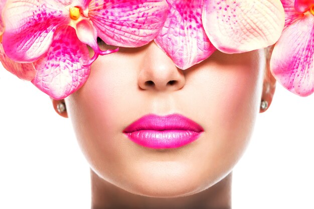 Schönes Gesicht der Frau mit hellem Lippenstift auf den Lippen und rosa Blumen - lokalisiert auf Weiß