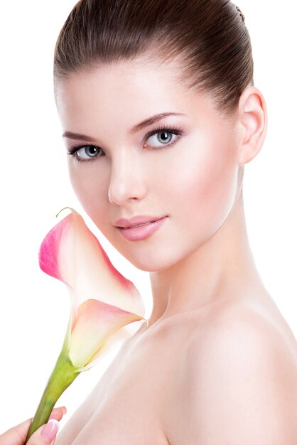 Schönes Gesicht der jungen hübschen Frau mit gesunder Haut und rosa Blumen auf Körper - lokalisiert auf Weiß.