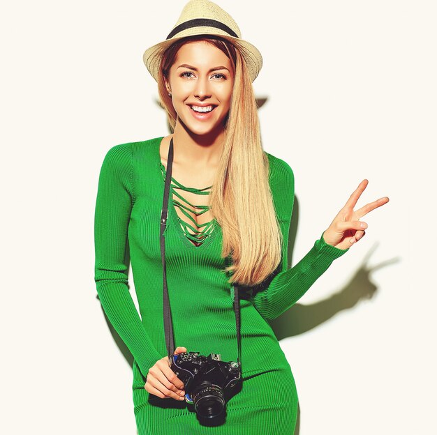 schönes glückliches nettes blondes Frauenmädchen in der zufälligen Sommergrün-Hippie-Kleidung macht Fotos, die Retro- Fotoapparat halten