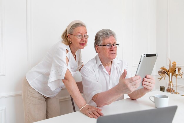 Schönes Großelternpaar, das lernt, ein digitales Gerät zu verwenden
