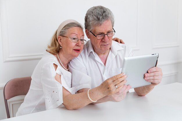 Schönes Großelternpaar, das lernt, ein digitales Gerät zu verwenden