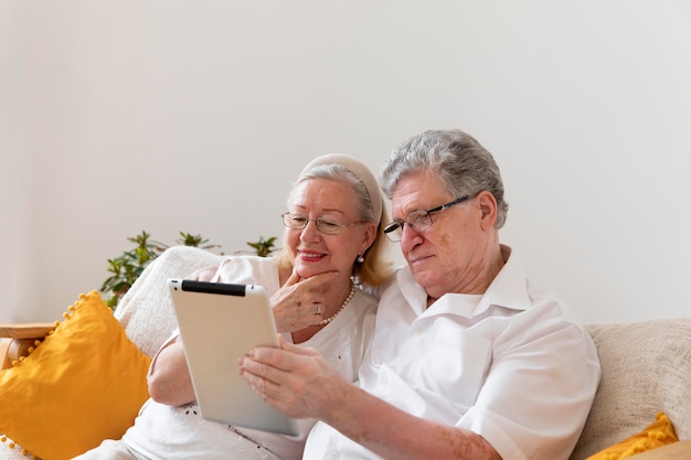 Schönes großelternpaar, das lernt, ein digitales gerät zu verwenden