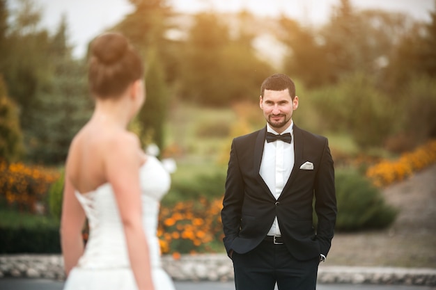 Schönes Hochzeitspaar, das einander im Park gegenübersteht