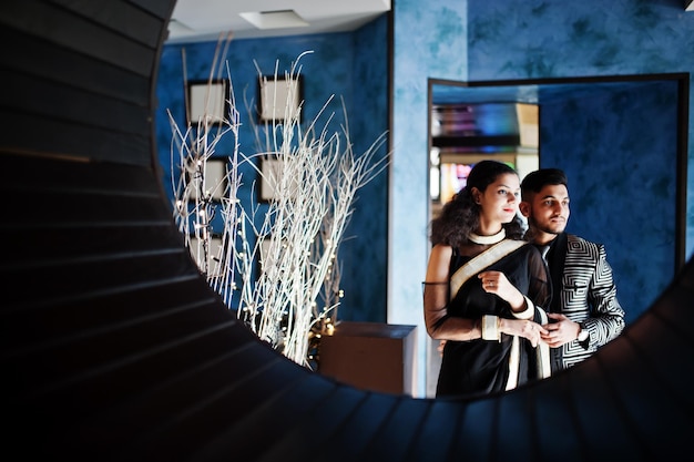 Kostenloses Foto schönes indisches paar in liebeskleidung im saree und elegantem anzug posiert im restaurant im runden kreis an der wand