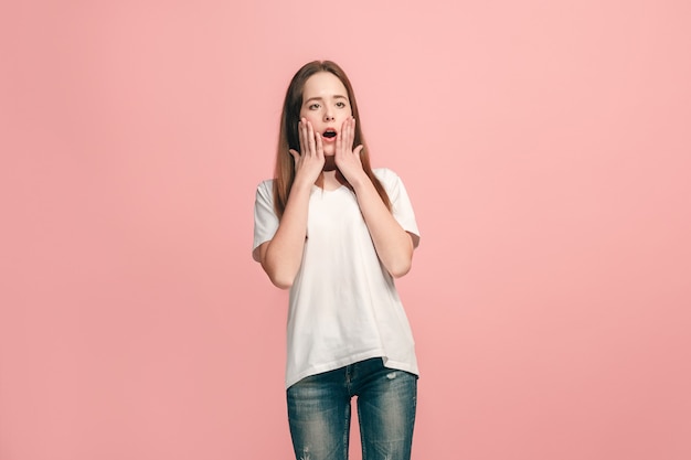 Schönes jugendlich Mädchen, das überrascht auf rosa Wand sucht