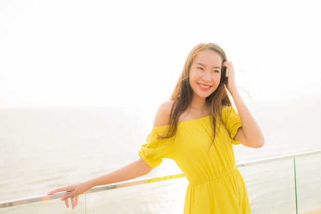 Schönes junges asiatisches Frauenlächeln des Porträts glücklich und entspannen sich am Balkon im Freien mit Seestrand und oce