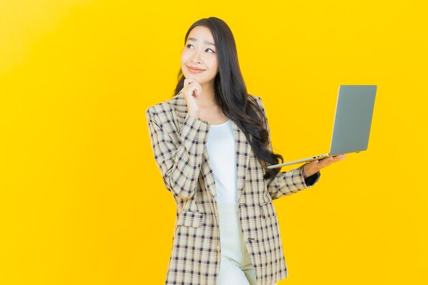 Schönes junges asiatisches Frauenlächeln des Porträts mit Computerlaptop