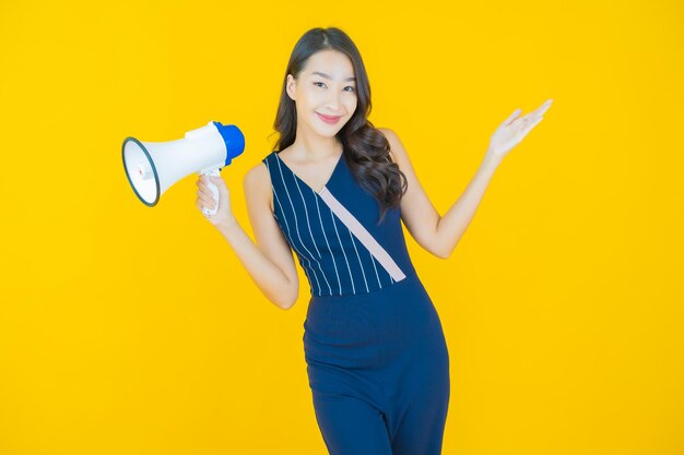 Schönes junges asiatisches Frauenlächeln des Porträts mit Megaphon an