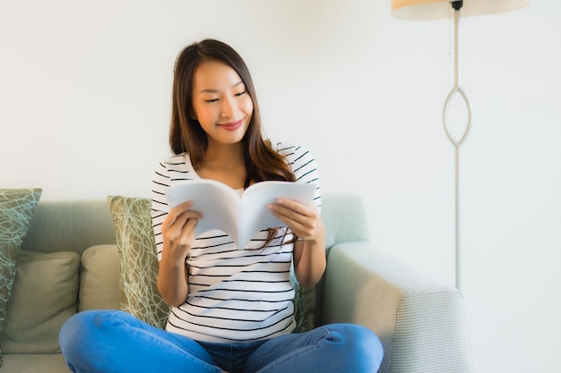 Schönes junges asiatisches Frauenlesebuch des Porträts mit Kaffeetasse