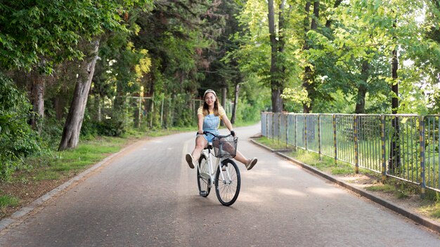 Schönes junges Mädchen, das Fahrrad draußen reitet