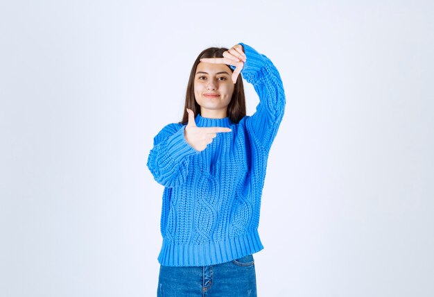 Schönes junges Mädchen, das Rahmen mit Handpalmen und Fingern tut.