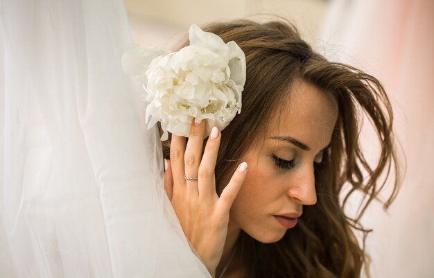 schönes junges Mädchen mit langen Haaren mit echten Blumen in den Händen des weichen Geheimnisses