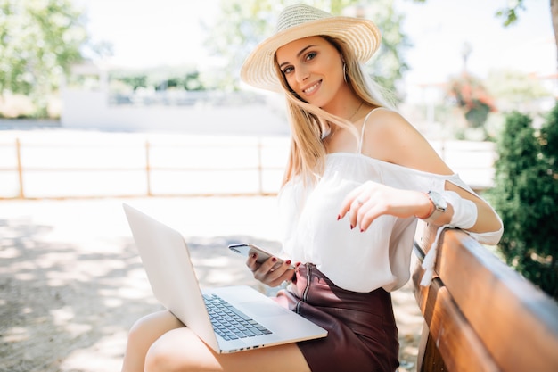 Schönes junges Mädchen mit Laptop im Sommerpark