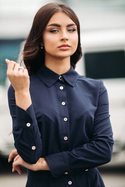 Schönes junges Mädchen mit Make-up glättet elegant ihr langes kastanienbraunes Haar mit einer Hand