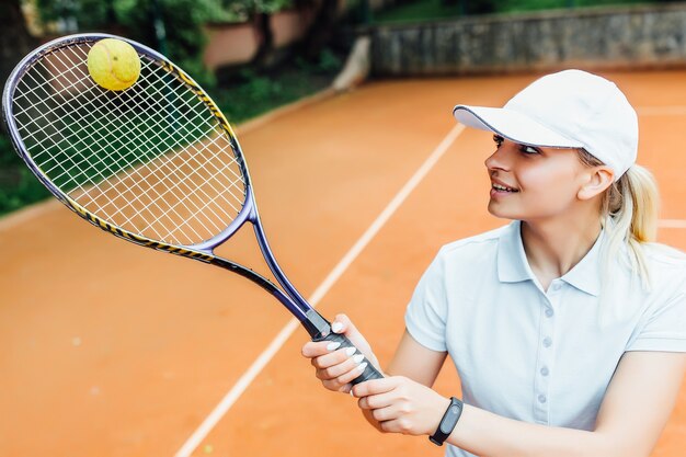 Schönes junges Mädchen mit süßem Gesicht l auf einem offenen Tennisplatz, der Tennis spielt. Spielbereit.