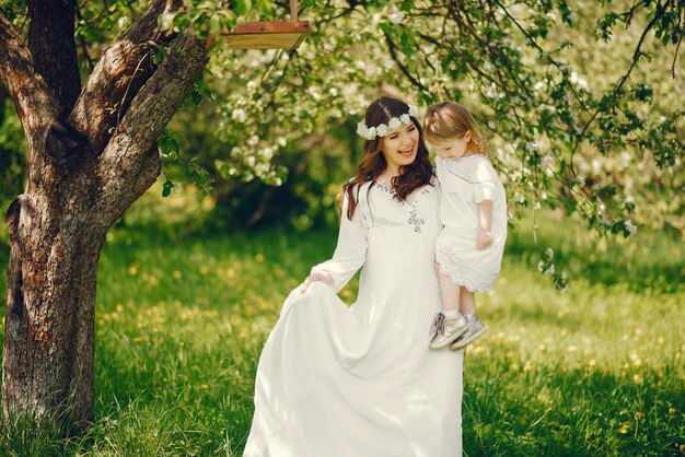 schönes junges schwangeres Mädchen in einem langen weißen Kleid mit kleinem Mädchen