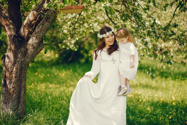 schönes junges schwangeres Mädchen in einem langen weißen Kleid mit kleinem Mädchen