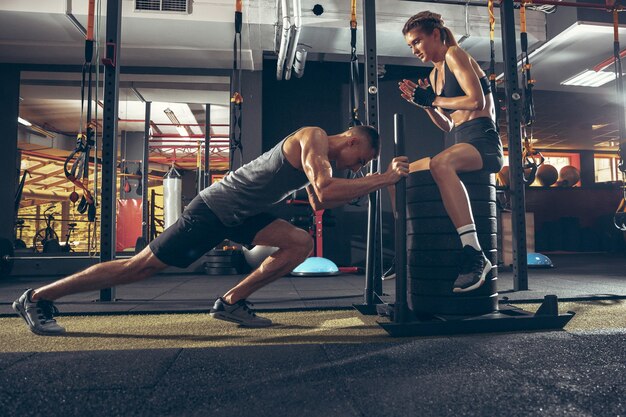 Schönes junges sportliches Paar, das zusammen Training im Fitnessstudio trainiert