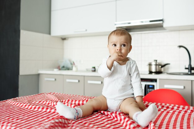 Schönes kleines Baby, das auf Küchentisch sitzt