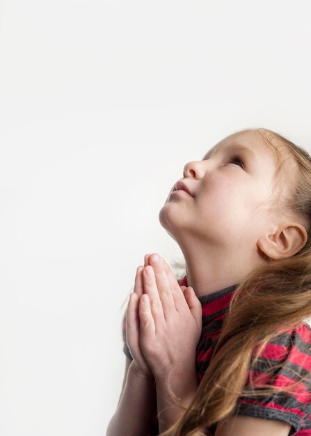 Schönes kleines Mädchen, das mit Kopienraum betet