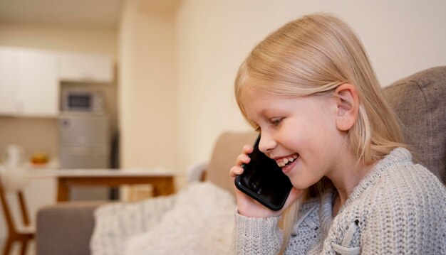 Schönes kleines Mädchen mit Smartphone zu Hause