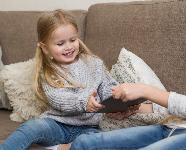 Schönes kleines Mädchen mit Tablette zu Hause