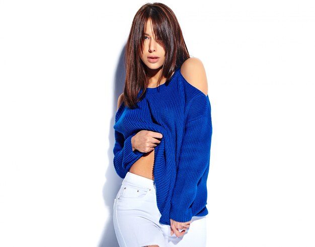 Schönes lächelndes Hipster-Brünettenfrauenmodell, das stilvollen blauen Sommerpullover lokalisiert auf weißem Hintergrund zieht