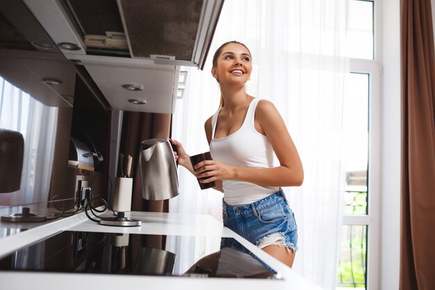 Schönes lächelndes junges Mädchen machen Kaffee