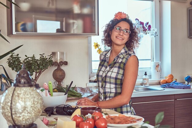 Schönes lockiges hispanisches Mädchen, das in ihrer Küche kocht.