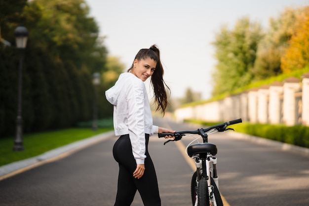 Schönes Mädchen, das am weißen Fahrrad aufwirft